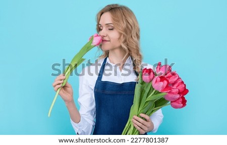 girl smile in apron with spring tulip flowers on blue background