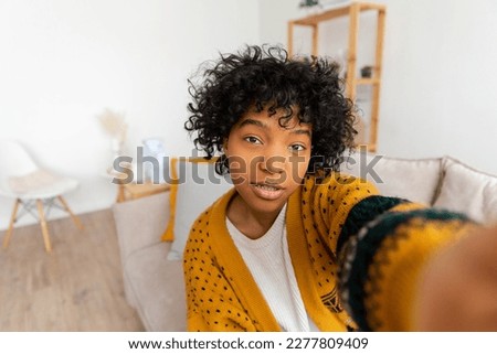 Happy african american teen girl blogger smiling face talking to webcam recording vlog. Social media influencer woman streaming making video call at home. Headshot portrait selfie webcamera view Royalty-Free Stock Photo #2277809409