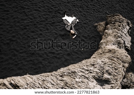 graphic photo of a girl lying on black sand