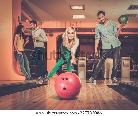 Blond smiling girl throwing ball in a bowling club