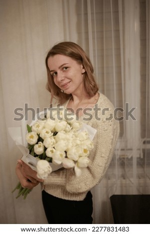 white tulips. spring flowers. women's Day. the girl holds a bouquet of white tulips in her hands