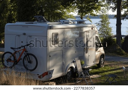 White camper van with bike on a  camping pitch of a natural campsite in Sweden.	