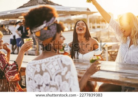 Happy girls having fun drinking cocktails at bar on the beach - Party and summer concept - Focus on latin girl face Royalty-Free Stock Photo #2277839383