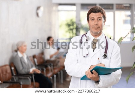 male medical eceptionist affably waiting for patients of clinic in waiting room