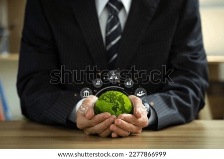 ESG environmental social governance business strategy investing concept. Businessman holding green world ball with Esg icons.Ethical and sustainable investing. Enhance ESG alignment of investments. Royalty-Free Stock Photo #2277866999