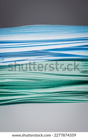 Vertical picture of biscay green and blue surgical masks overlaid in layers on white background, Bacteria protection concept.