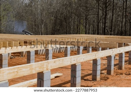 Work on new custom homes concrete block foundation installing wood floor joists trusses Royalty-Free Stock Photo #2277887953