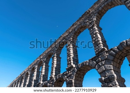 View of beautiful Roman aqueduct of Segovia Spain and tiny plane against a blue sky  Royalty-Free Stock Photo #2277910929