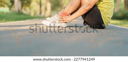 Young adult male with his muscle pain during running. runner man having leg ache due to Ankle Sprains or Achilles Tendonitis. Sports injuries and medical concept Royalty-Free Stock Photo #2277941249