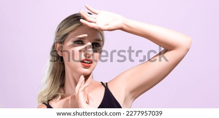 Closeup young blond hair woman with perfect skin and soft alluring facial makeup raise her hand cover her face from bright sunlight in pink isolated background for skincare sunscreen product. Royalty-Free Stock Photo #2277957039