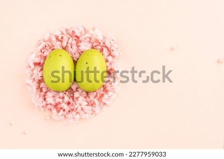 Two green painted Easter eggs in a nest of pink flowers. Minimal easter creative background.