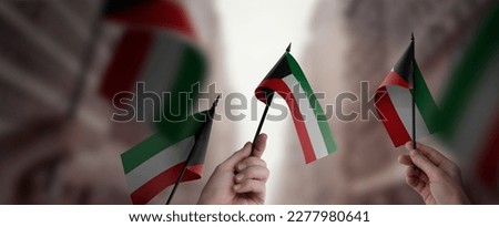 A group of people holding small flags of the Kuwait in their hands. Royalty-Free Stock Photo #2277980641