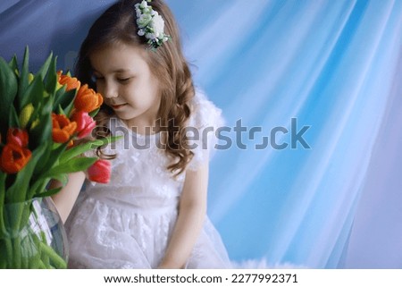 Beautiful girl in white dresses with a magnificent bouquet of first tulips. International Women's Day. Girl with tulips.