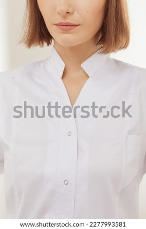 Cropped close up details of medical scrubs clothes. Beautiful young female model. White studio background. Catalog photo shoot in minimalist style Royalty-Free Stock Photo #2277993581