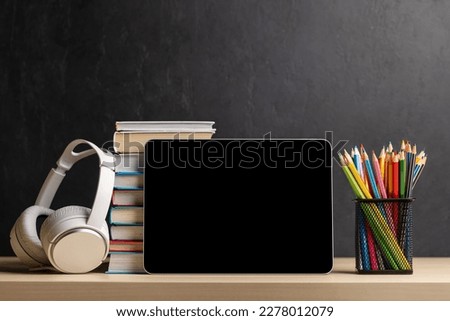 Tablet with colorful pencils and stack of books. With blank screen for your text or app