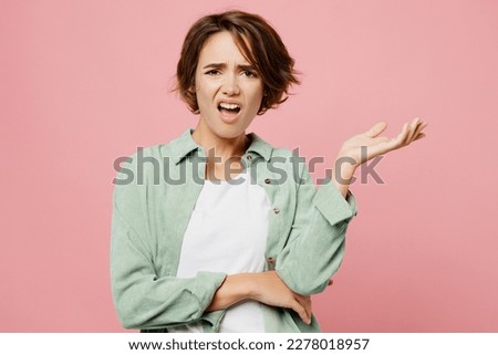 Young shocked indignant outraged woman 20s she wear green shirt white t-shirt look camera spread hands say what isolated on plain pastel light pink background studio portrait. People lifestyle concept Royalty-Free Stock Photo #2278018957