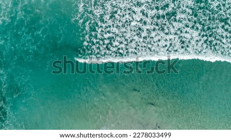 Above the ocean, aerial view at the waves and surface near shoreline - Drone viewpoint.