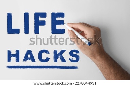 Man writing words Life Hacks with marker on whiteboard, closeup