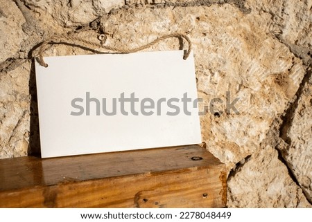 old stone wall and polished wood with a white hanging picture sign with empty free space for template or blank copy area 