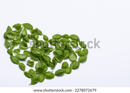 Heart shape arranged from basil leaves on white background