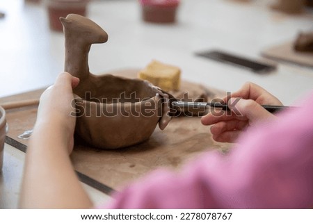 A child paints a clay craft. Pottery school