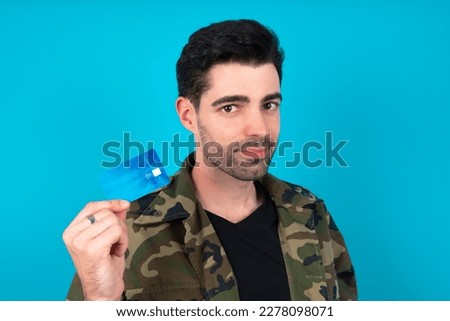 Close up photo of optimistic Young man standing over blue studio background hold card