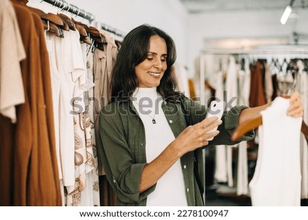 Small business owner taking a picture of a clothing item in her store in order to advertise it to her followers on social media. Female entrepreneur marketing her fashion store online.
