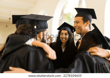 Cheerful graduates friends hugging in a circle and laughing while looking excited during their college graduation ceremony Royalty-Free Stock Photo #2278104655