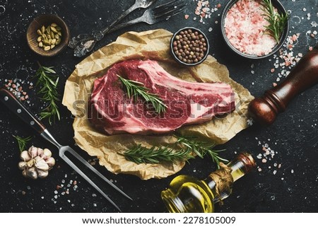 dry aged steak on the bone with spices and rosemary. On a black stone table. Top view. Royalty-Free Stock Photo #2278105009
