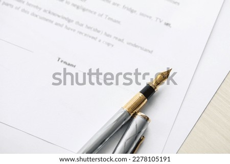 Fountain pen and documents on wooden table, above view. Notary services