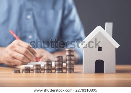 Money saving for house or Financial for real estate concept. Man making calculate note on book and coin stacked on the wooden table. Keeping fund for purchase the residence idea. Studio shot. Royalty-Free Stock Photo #2278110895