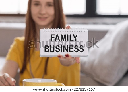 Smiling woman holding brochure with Family Business text on grey background.