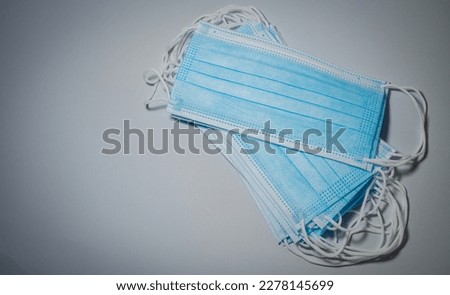 Blue surgical masks stacked in layers on gray background, Bacteria protection concept.