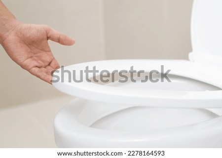 close up hand of a woman closing the lid of a toilet seat. Hygiene and health care concept. Royalty-Free Stock Photo #2278164593