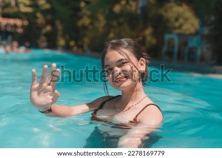 A happy young asian lady enjoying a dip at a swimming pool. Enjoying her summer vacation.