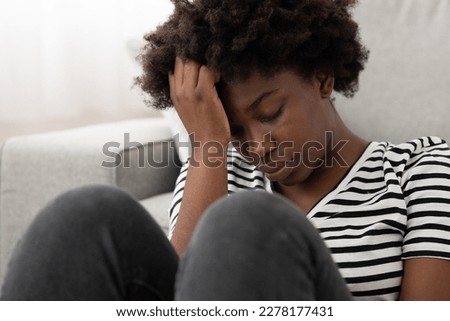 Closeup of sad African American young woman overthinking. Depression and mourning concept