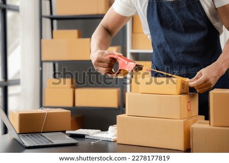 An online shop owner man is packing orders, he is an internet shop operator selling products through online shopping platform website. The concept of selling products on the internet. Royalty-Free Stock Photo #2278177819