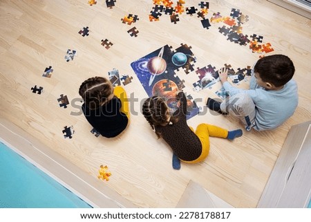 Children connecting jigsaw puzzle pieces in a kids room on floor at home.  Fun family activity leisure.  Royalty-Free Stock Photo #2278178817
