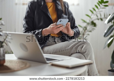 Young woman using laptop and mobile phone sitting at workplace at home, remote work Royalty-Free Stock Photo #2278183213