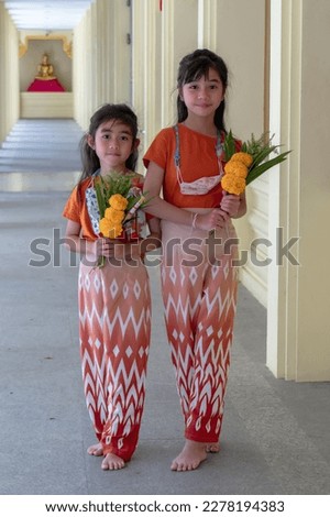 Two young girls stand in front of a temple 