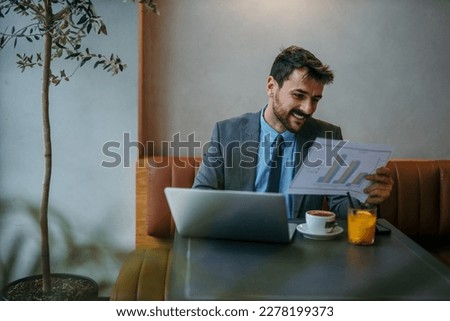 Happy businessman working at a restaurant using a laptop computer and checking stats. Royalty-Free Stock Photo #2278199373
