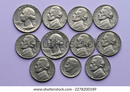 Assortment of old nickel, dime and quarter coins on purple background.