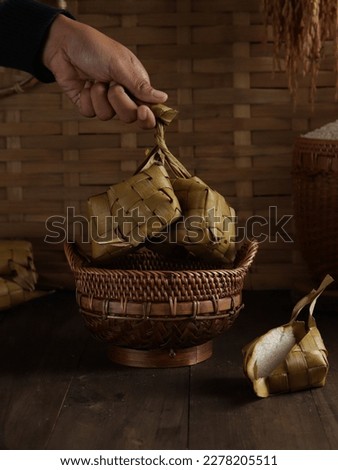 A hand of woman held ketupat or South East Asian rice cakes bundle, often prepared for festivities and very popular dish during Eid Mubarak celebratory in Indonesia and Malaysia Royalty-Free Stock Photo #2278205511