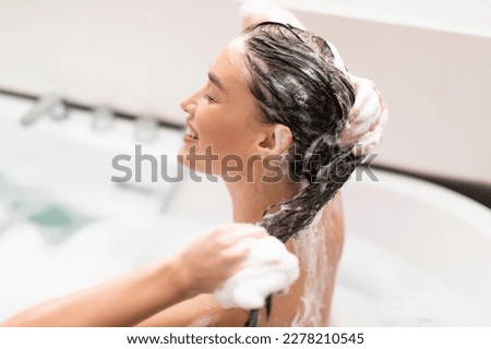 Haircare. Side View Of Woman Washing Head Caring For Long Brown Hair Sitting In Bathtub Indoors. Happy Lady Applying Shampoo Posing With Eyes Closed In Modern Bathroom, Selective Focus Royalty-Free Stock Photo #2278210545