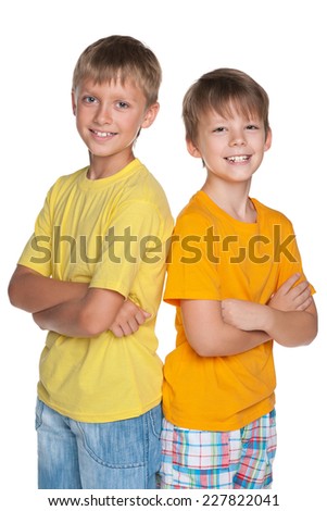 Two smiling young boys are standing together against the white background