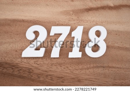 White number 2718 on a brown and light brown wooden background.