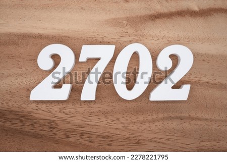 White number 2702 on a brown and light brown wooden background.
