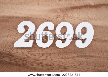 White number 2699 on a brown and light brown wooden background.