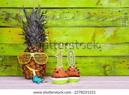 Creative card postcard happy birthday with number  10. Background character pineapple in festive glasses. Copy space anniversary card on yellow colorful wooden background.
