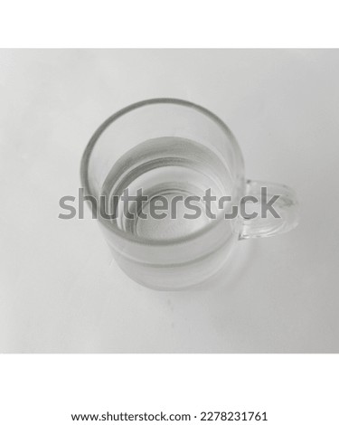 a white glass filled with half a glass of water, a glass that many people use to drink